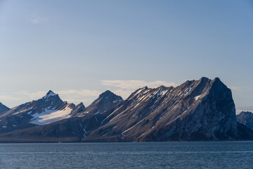 Sharp mountain peaks sticking up out of the Arctic Ocean in Svalbard, as a nature background
