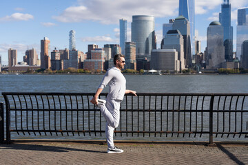 Athlete stretching to improve flexibility. Athlete stretching muscles and preparing for workout. Stretch routine of athlete outdoor. Athlete stretching his muscles after running. Dynamic stretching