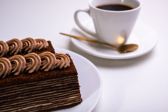 chocolate cream cake with tea, coffee with a piece of spartak, on a light background.