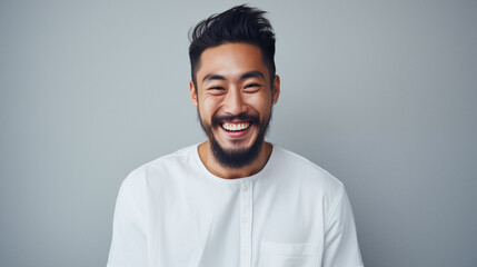 Obraz premium Happy young asian man with beard and stylish hairstyle. Positive expression studio portrait. AI generated.