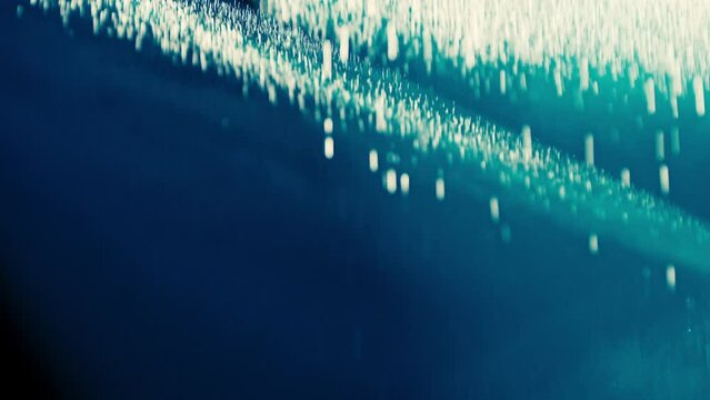Abstract dark background with blue cold flashing light beam spot and laser illuminate falling rain and smoke. Sharp laser beams and narrow light streaks flashing rapidly.