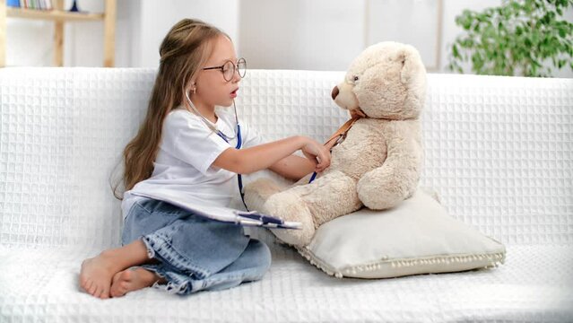 Little baby girl playing doctor physician practitioner listening breath heartbeat bear toy patient