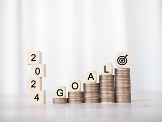 Wooden block with word GOAL on stack of coins and number 2024. The concept of saving money for...