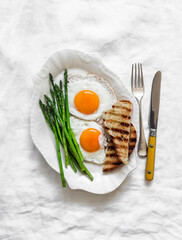 Simple breakfast, snack, brunch - fried eggs and asparagus on a light background, top view