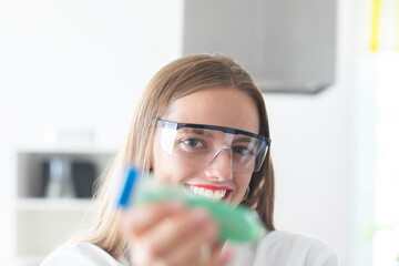 young scientist with  lab glasses and holding green tube