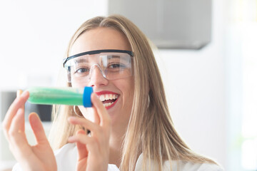 young scientist with  lab glasses and holding green tube