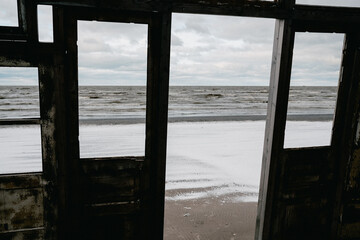 Stunning seascape view of Liepaja, Latvia through a rustic window frame.