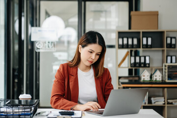 Young beautiful woman using laptop and tablet while sitting at her working place. Concentrated at work.