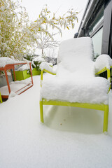 Snow-covered all-season metal furniture with snow-covered table and chairs on a roof terrace