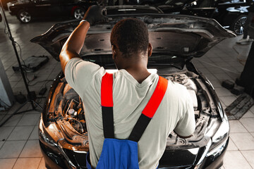 Back view of an African male mechanic repairing car in garage