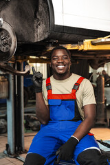 Portrait of young african man car service worker wearing uniform standing in garage