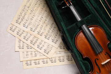 Violin, bow in case and music sheets on light grey table, top view