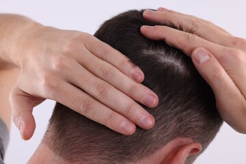 Man examining his hair and scalp on white background, closeup