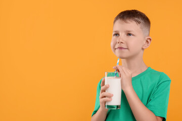 Cute boy with glass of fresh milk on orange background, space for text
