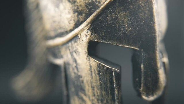 A close up macro detailed slow tilt up shot of a spartan face design, warrior metal bronze helmet, on a 360 rotating stand, studio lighting, 4K smooth movement