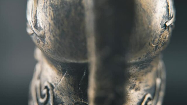 A close up macro detailed slow tilt up shot from behind of a spartan face design, warrior ancient greek bronze helmet, on a 360 rotating stand, studio lighting, 4K smooth movement