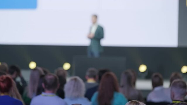 Handheld shot of male speaker giving presentation to diverse businesspeople during global workshop