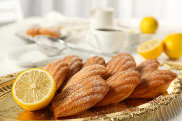 Madeleine cakes, lemons and dishes on light background, close up