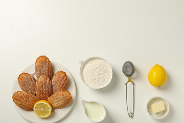 Madeleine cakes, cream, flour, butter and lemon on white background, space for text