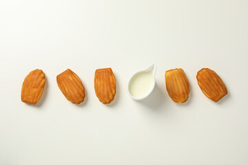 Madeleine cakes and cream on white background, top view