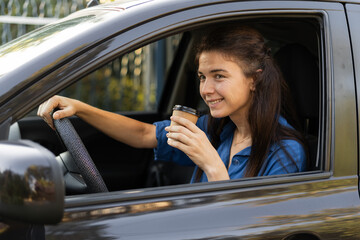 Attractive businesswoman driving a car drinking coffee. She is looking at road