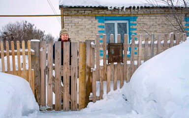 a beautiful woman stands at the gate of her house on a winter day