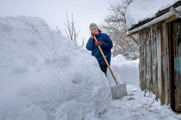 beautiful woman removes snow with a shovel on a winter day