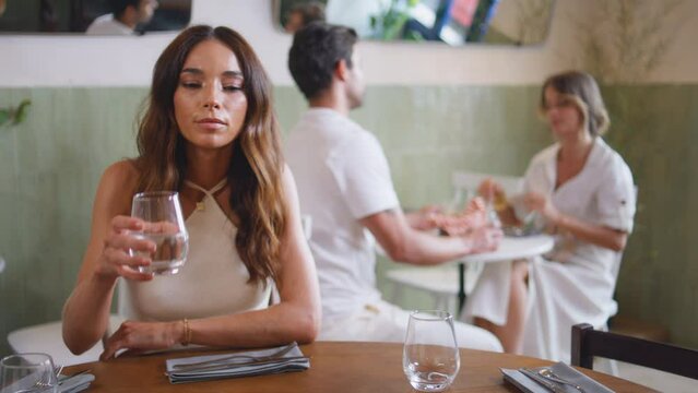 Single woman drinking water at cafe closeup. Girl waiting boyfriend failed date