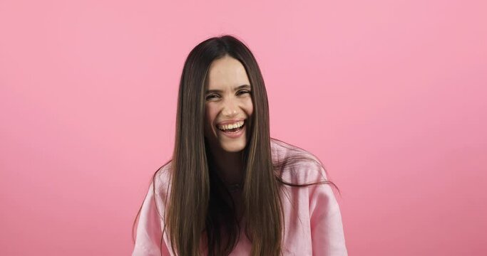 Young excited cheerful funny brunette woman look camera laugh smiling watch comedy movie, listening joke, pointing index finger on you isolated on pink background studio portrait.