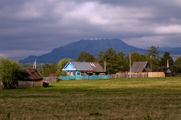 Fototapeta na wymiar the village of Verkhnearshinsky in the Beloretsk region of Bashkortostan against the backdrop of the Kumardak ridge on a cloudy day