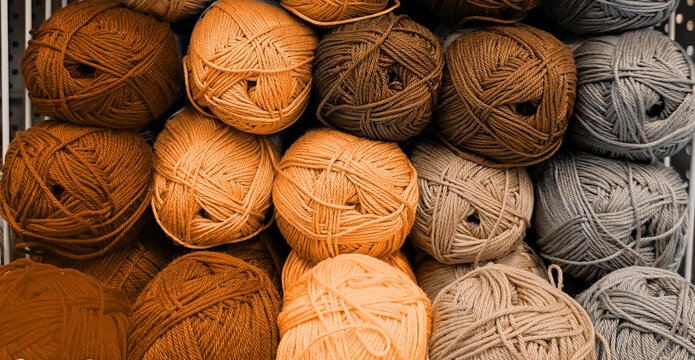 Colorful of Yarn Balls Wool in a Fabric Shop. Background from colored acrylic yarn. Skeins of thread close-up. Materials for needlework, for knitting and crocheting. Peach Fuzz colour of 2024 year
