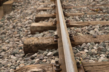 Fototapeta na wymiar Detail of the rail of the railway track, stones, screw and wooden sleepers. Concept of means of transport.