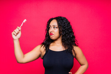 Obraz premium Happy African American woman brushes teeth. Dental hygiene concept. Isolated on red background.