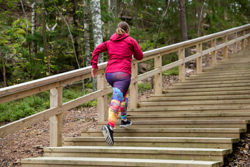 Athletic middle-aged woman running up the Fitness Stairs in a natural park in the woods