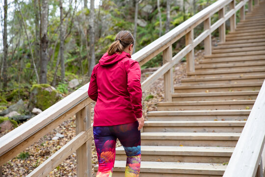 Athletic middle-aged woman running up the Fitness Stairs in a natural park in the woods