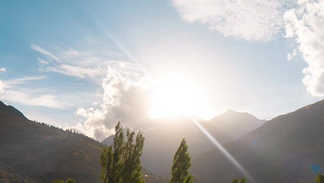 4k time lapse of setting sun and clouds in sky in mountain valley of Keylong, India. Sunset on mountains. Summer landscape of mountains, clouds and tree. Sun setting over small town of Lahaul