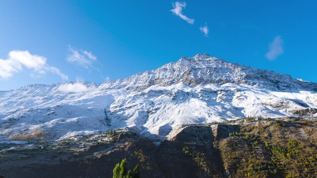 Time lapse of snow covered mountains and soft clouds moving during sunrise in Keylong, Lahaul, India. Fresh snow on mountain with blue sky in winter. Winter snow landscape.