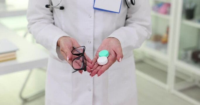 Ophthalmologist hand holds contact lenses and glasses