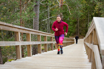 Athletic middle-aged woman running up the Fitness Stairs in a natural park in the woods