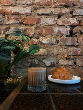 Close-up of a moccachino and croissant on a table in a rustic setting