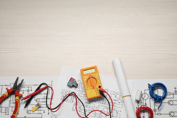 Flat lay composition with wiring diagrams and digital multimeter on white wooden table, space for...