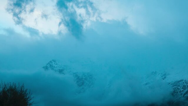 Winter mountain timelapse on the Himalayas. Dark moody clouds moving over snow covered mountain peaks in Keylong, Lahaul, India. Moody winter weather. Winter landscape.
