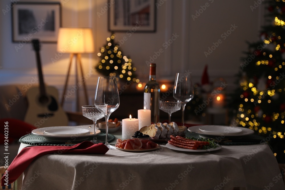 Poster Christmas table setting with burning candles, appetizers and dishware in room