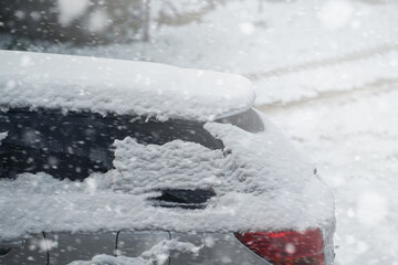 Car covered with a thin layer of snow. Vehicle after snowstorm parked on the street side. Rear side of the car with snow. Estate wagon. Touring wagon in winter.