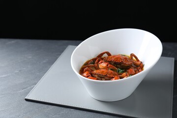 Delicious boiled crabs with sauce on grey table, space for text