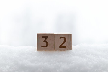 Temperature, weather in winter. Close-up of a wooden cube with the number 32 degrees Fahrenheit in...