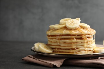 Tasty pancakes with sliced banana and honey on gray table, space for text