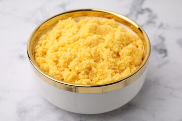 Tasty cornmeal in bowl on white marble table, closeup