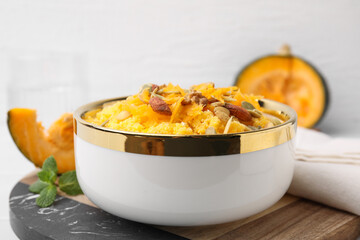 Tasty cornmeal with nuts, pumpkin and seeds in bowl on table, closeup
