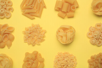 Different types of pasta on yellow background, flat lay
